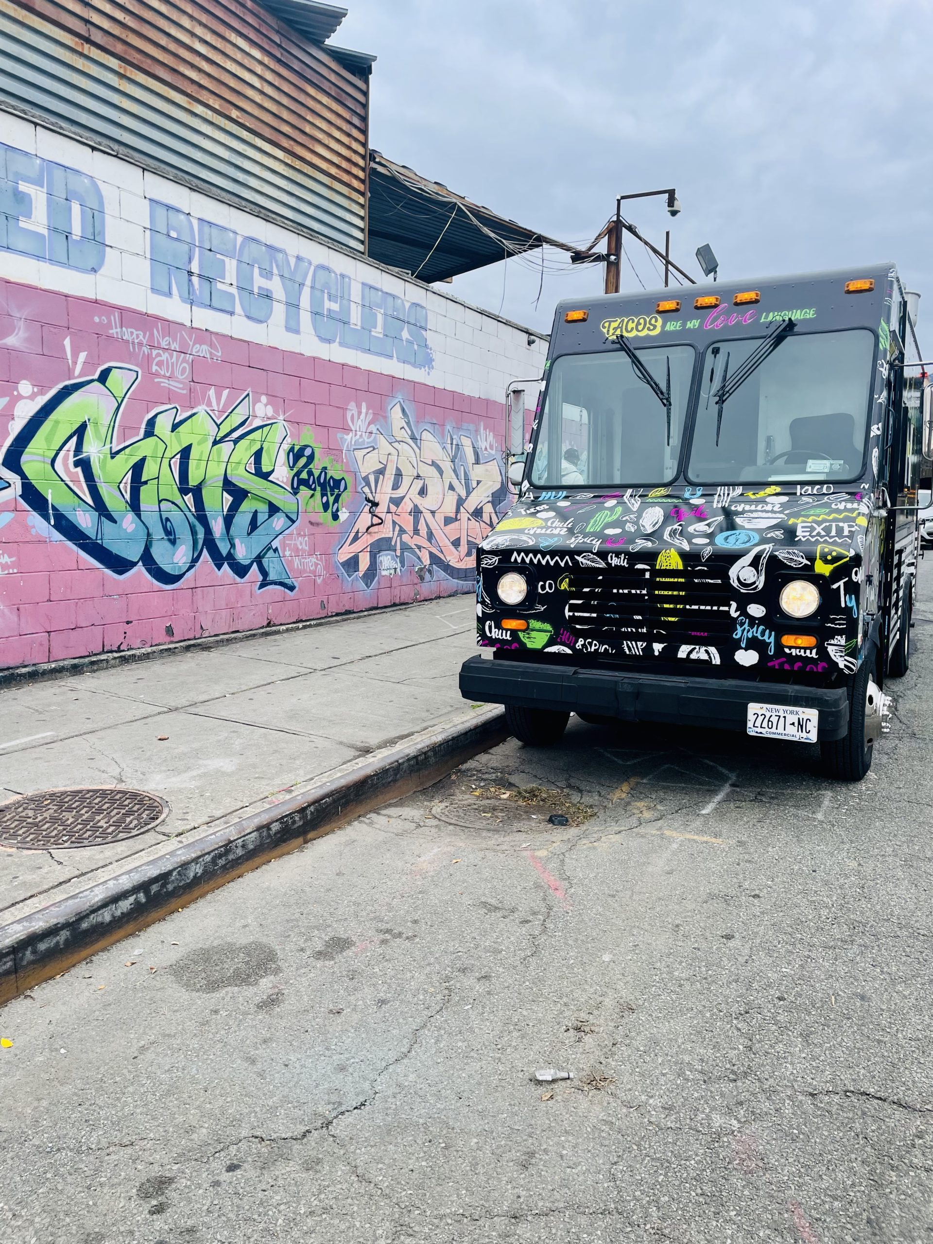 Kinky Taco Truck parked by some wall graffiti on the street of New York City